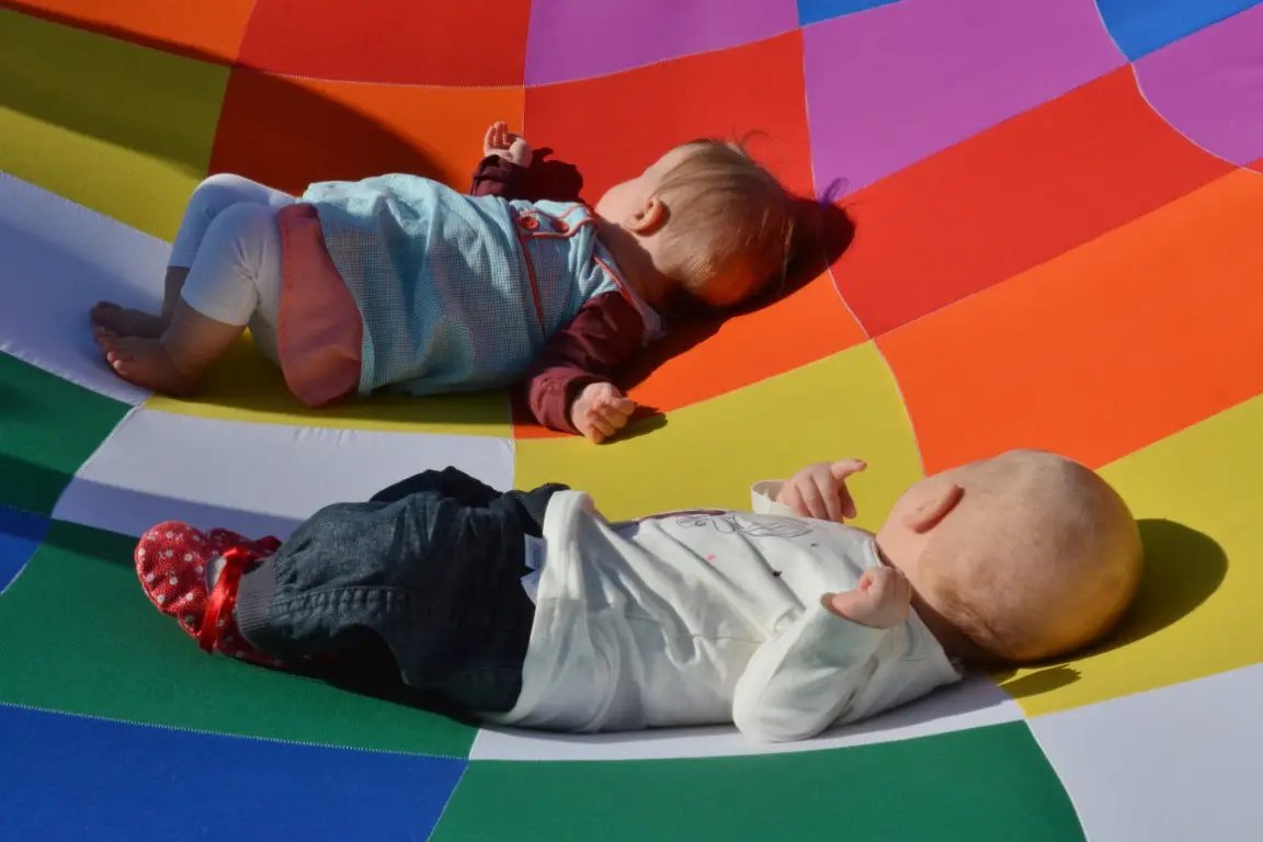 Foto - Kinderen liggen op kleurrijk doek